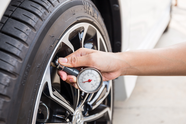 Person using a tire pressure gauge to check car tire pressure | Gil's Garage Inc of Half Moon in Clifton Park, NY